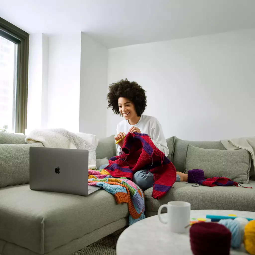 How to Go Live on OnlyFans - A creator is knitting in front of her laptop, giving fans an authentic, relaxed view of how she makes her art