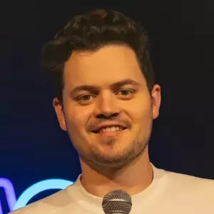 Comedian Joe Eames poses in front of the LMAOF logo