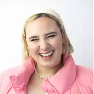 Comedian Maddie Houlbrook-Walk smiles at the camera.