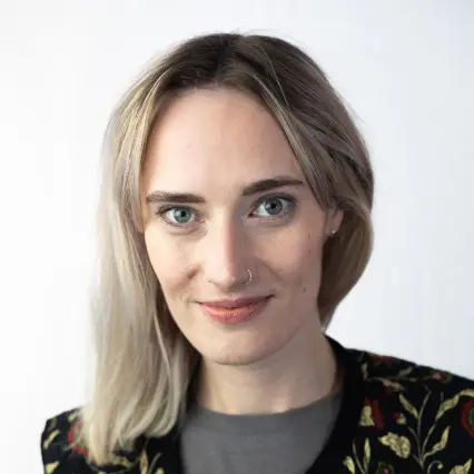 Comedian Steph Bradshaw smirks at the camera.
