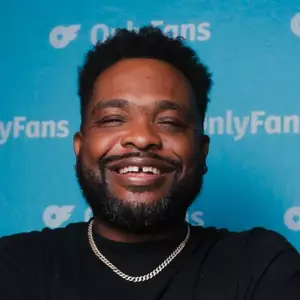 Comedian Clark Jones poses in front of the OnlyFans logo
