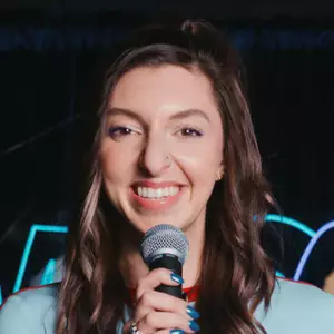 Comedian Katie K. poses in front of the OnlyFans logo.