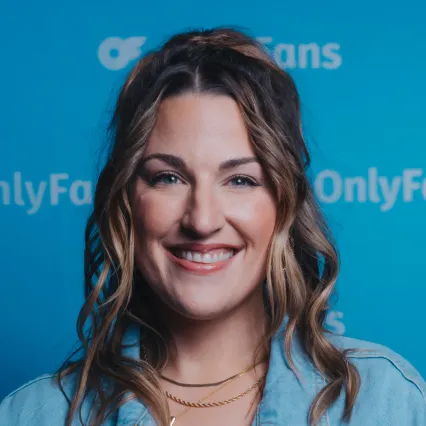 Lindsay_Adams Lindsay Adams poses in front of the OnlyFans backdrop.