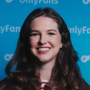 Macey Isaacs poses in front of the OnlyFans backdrop.