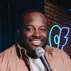 Rob Smallwood poses in front of the OnlyFans logo.