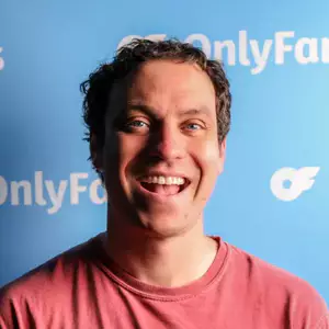 Comedian Brent Pella poses in front of the LMAOF logo.