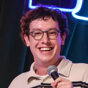 Comedian Jack Shaw poses on stage in front of the LMAOF logo.