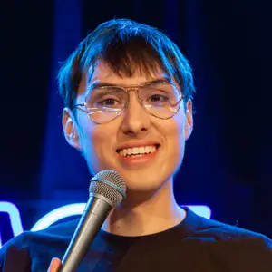 Comedian Luis Arevalo poses on stage in front of the LMAOF logo