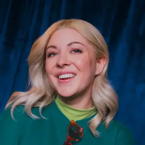 Comedian Jessie 'Jetski' Johnson smiles to camera in front of a blue curtain.