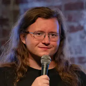 Comedian Rob Stant poses with a mic in front a brick wall at LMAOF 107 in New York