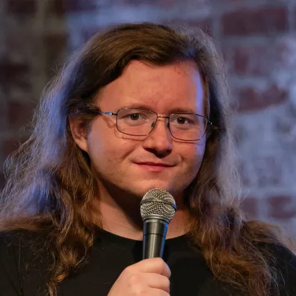 RobStant Comedian Rob Stant poses with a mic in front a brick wall at LMAOF 107 in New York