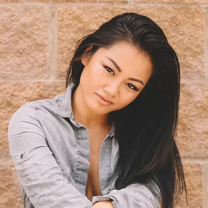 Bi Nguyen, MMA fighter, poses in front of a brick wall wearing a long sleeve shirt.