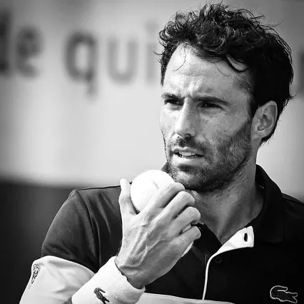 Jonathan Eysseric, tennis player, holds a ball near his face in a black and white photo.