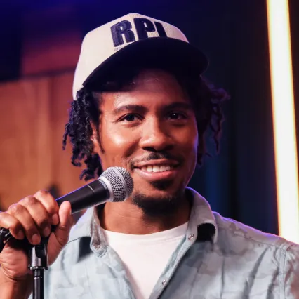 Darius Bennett speaks into a microphone as he performs on the LMAOF stage.