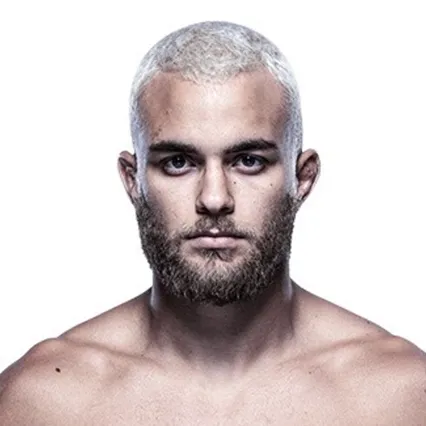 MMA fighter Allan Begosso facing forward in a studio portrait, with short bleached hair and a beard against a neutral background.