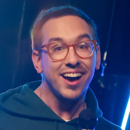 Stand-up comedian Martin Phillips holds a microphone and smiles.
