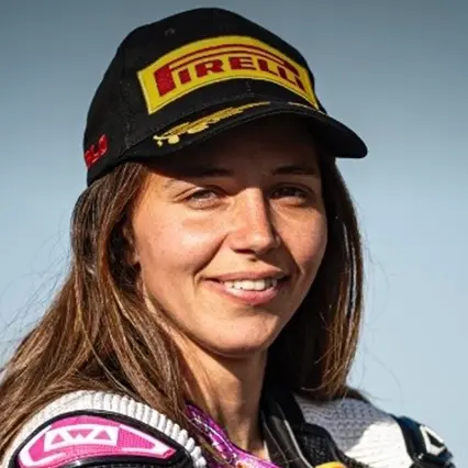 Beatrice Barbera, professional motorcycle racer, looks to camera in her race gear and a Firelli baseball cap.