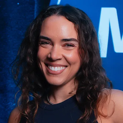 Estefania Baha, comedian, smiles in front of the LMAOF logo.