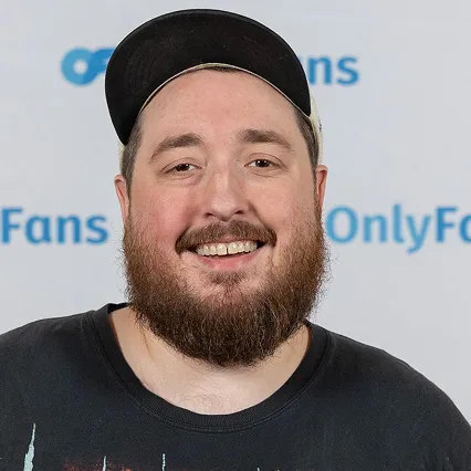 Blake Hammond, stand-up comedian, smiles in a portrait wearing a black cap against an OnlyFans step-and-repeat backdrop.