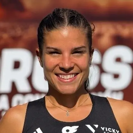 Cristina Polanco, professional distance runner, smiles while wearing her racing uniform.