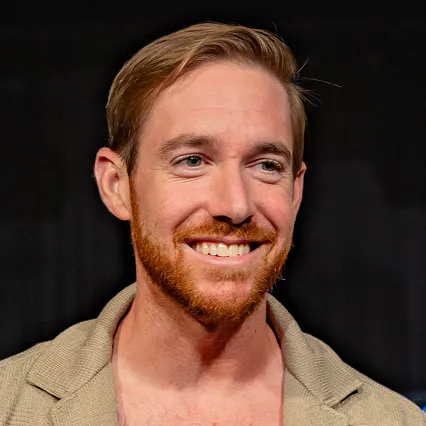 WillAbeles Will Abeles, stand-up comedian, smiles in a portrait against a dark stage backdrop.