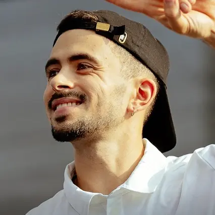 Varo Hernández, Spanish BMX Flatland rider, smiling in a white shirt and black cap.