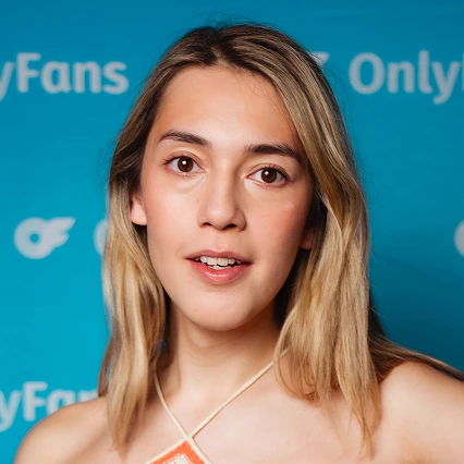 British comedian Alex Franklin poses in front of an OnlyFans backdrop.