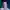 Comedian Kyle Rehl smiles to camera in front of a blue curtain.
